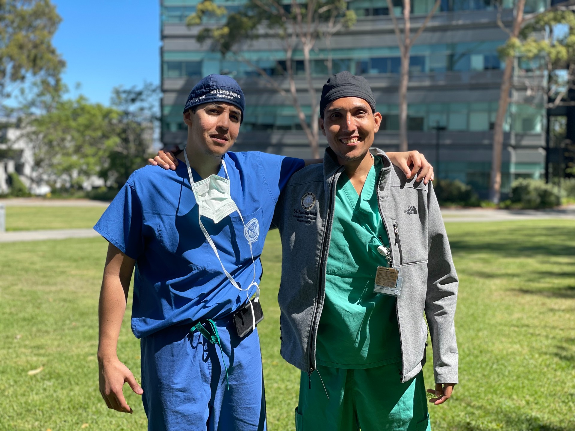 Hispanic neurosurgeons Drs. David Santiago-Dieppa and Alexander Tenorio standing together outside and wearing scrubs